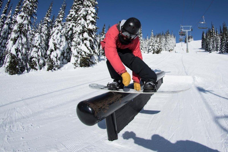 Snowboarder doing boardslide on a rail